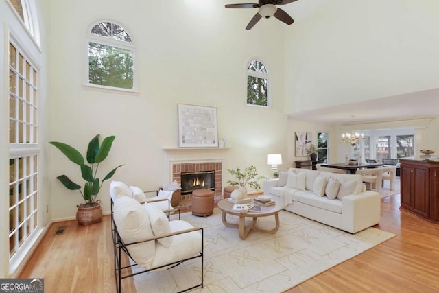 3711 Spinnaker Cir, Alpharetta, GA 30005 - living area featuring a brick fireplace, a high ceiling, light wood-type flooring, a chandelier, and ceiling fan