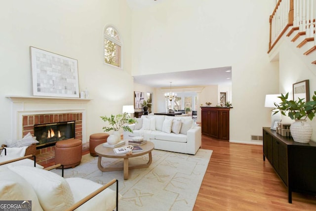 3711 Spinnaker Cir, Alpharetta, GA 30005 - living area featuring a towering ceiling, a chandelier, light wood finished floors, a brick fireplace, and stairs