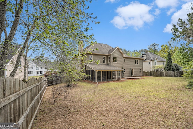rear view of property featuring a yard, a sunroom, a patio, and a fenced backyard