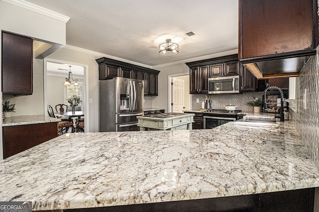 kitchen featuring ornamental molding, a sink, a notable chandelier, and appliances with stainless steel finishes
