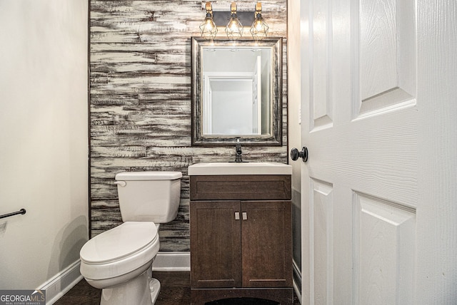 half bathroom featuring baseboards, vanity, and toilet
