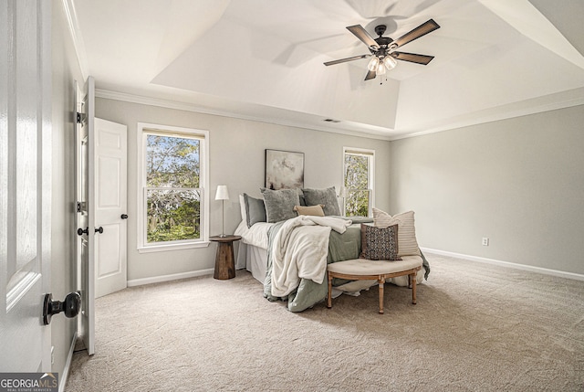 carpeted bedroom with baseboards, multiple windows, ornamental molding, and a raised ceiling