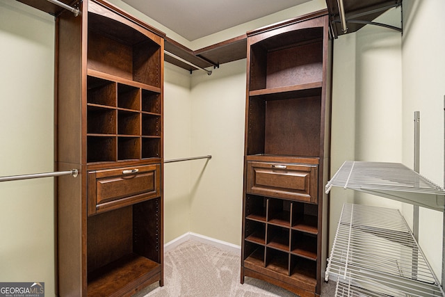 walk in closet featuring light colored carpet