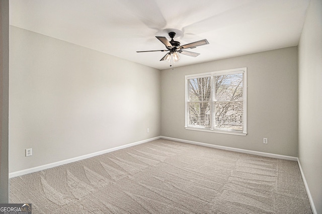 spare room with carpet floors, a ceiling fan, and baseboards
