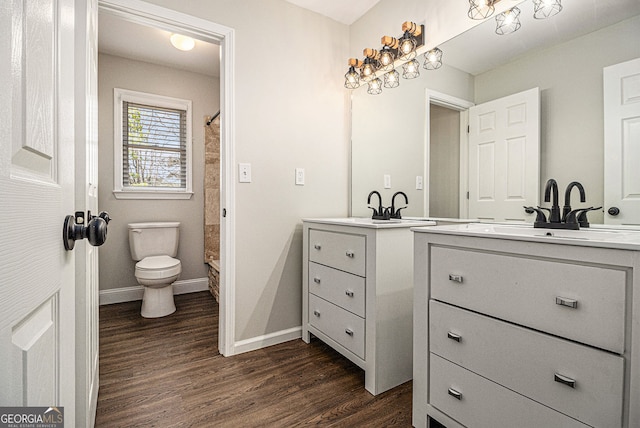 full bath with toilet, vanity, wood finished floors, and baseboards