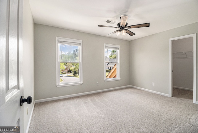 unfurnished bedroom with baseboards, visible vents, carpet, and a walk in closet