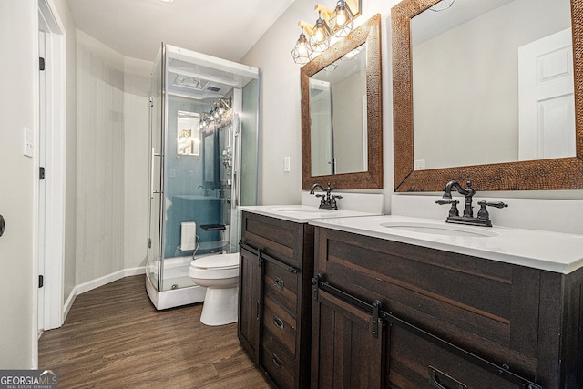 full bathroom with wood finished floors, a sink, a shower stall, and toilet