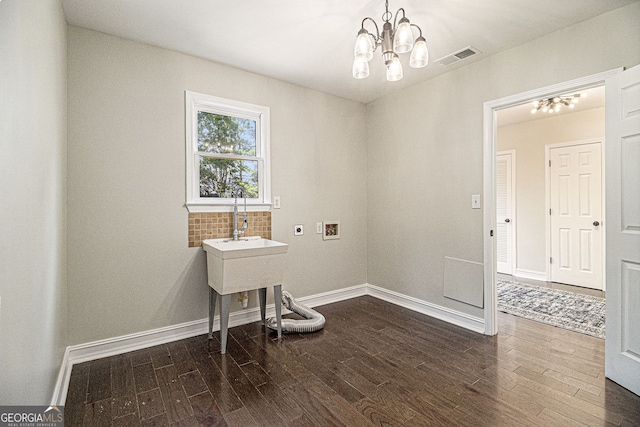 empty room with an inviting chandelier, dark wood-style flooring, visible vents, and baseboards