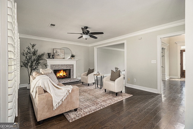 living area with ceiling fan, crown molding, a lit fireplace, and visible vents