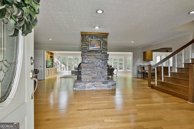 entrance foyer featuring a textured ceiling, wood finished floors, a wealth of natural light, and stairway