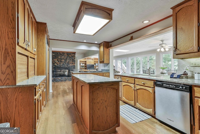 kitchen featuring a ceiling fan, brown cabinetry, a sink, and dishwasher