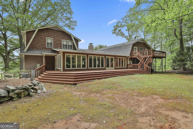 back of property with a wooden deck, a gambrel roof, a chimney, a sunroom, and stairs