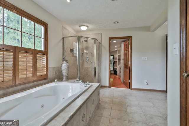full bathroom featuring baseboards, a whirlpool tub, a textured ceiling, tile patterned floors, and a stall shower
