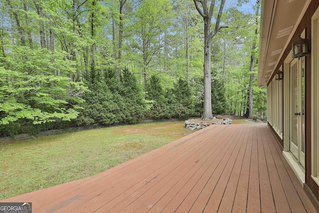 wooden terrace featuring a yard and a wooded view