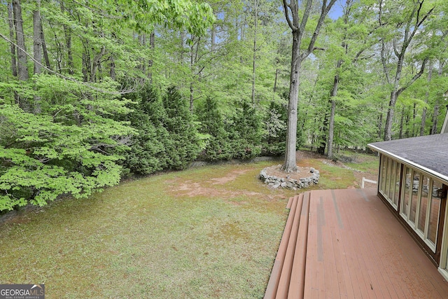 view of yard featuring a deck and a wooded view