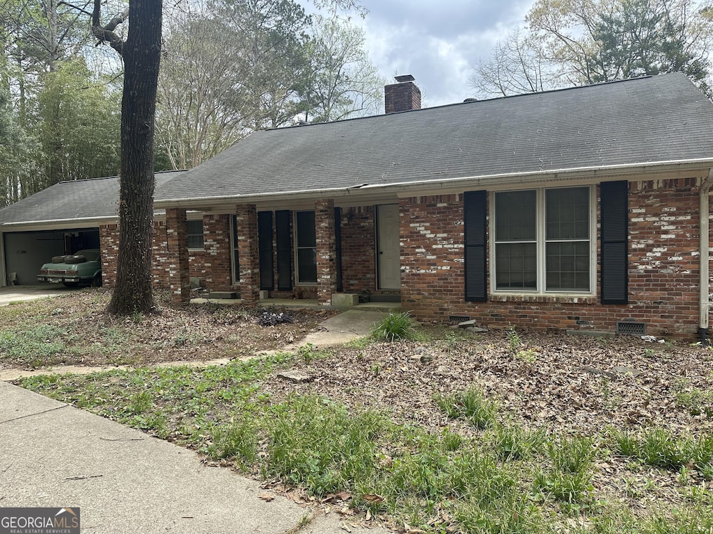 130 Sandy Dr, Stockbridge, GA 30281 - ranch-style house featuring brick siding, a shingled roof, an attached carport, and a chimney