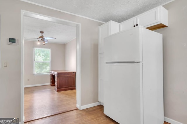 188 Paramount Dr, Eatonton, GA 31024 - kitchen with white cabinets, light wood finished floors, a textured ceiling, and freestanding refrigerator