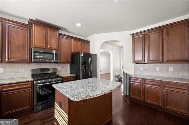 4735 Belcrest Way, Cumming, GA 30040 - kitchen with arched walkways, dark wood-style flooring, a center island, and appliances with stainless steel finishes