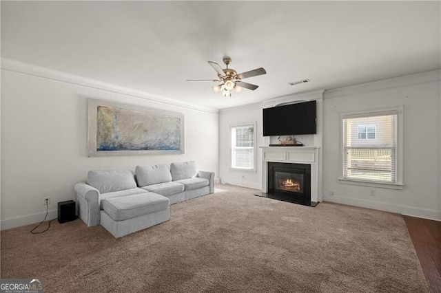 4735 Belcrest Way, Cumming, GA 30040 - living area featuring a glass covered fireplace, baseboards, ornamental molding, visible vents, and ceiling fan