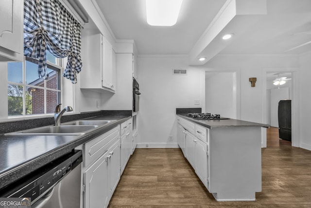 kitchen featuring a peninsula, gas stovetop, dishwasher, dark countertops, and a sink