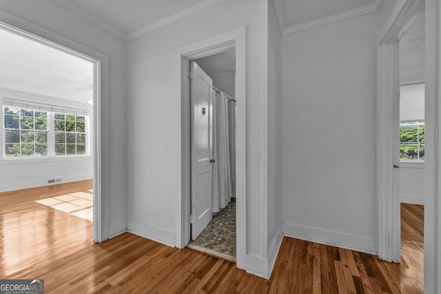 hall with plenty of natural light, visible vents, crown molding, and wood finished floors