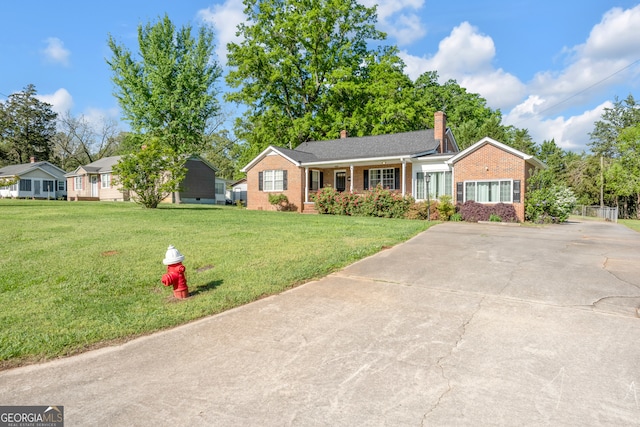 ranch-style home with brick siding, a chimney, a front lawn, and concrete driveway