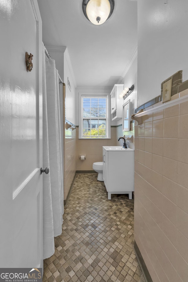 bathroom featuring vanity, tile walls, ornamental molding, and toilet