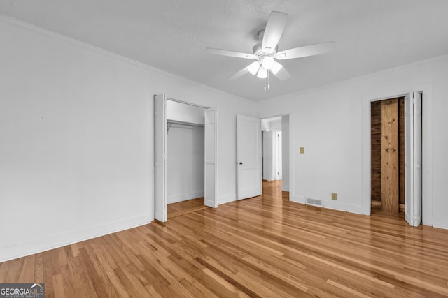 unfurnished bedroom featuring light wood finished floors, visible vents, baseboards, and ornamental molding