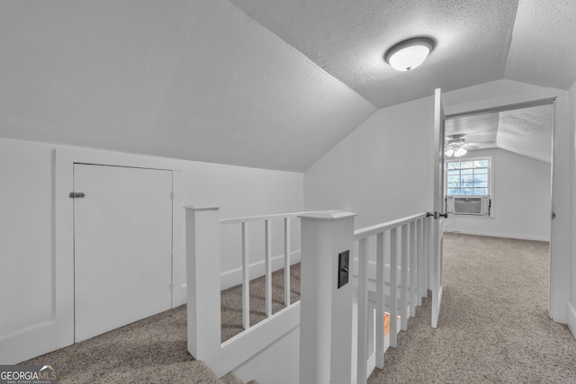 corridor with a textured ceiling, an upstairs landing, lofted ceiling, and carpet