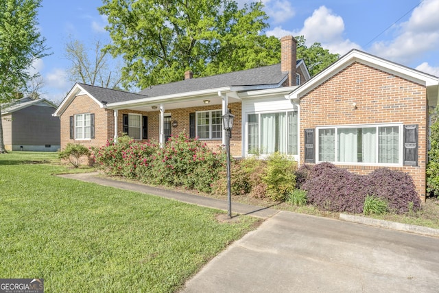 ranch-style house with brick siding, a front lawn, and a chimney