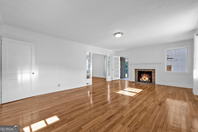 unfurnished living room featuring a brick fireplace, wood finished floors, and baseboards