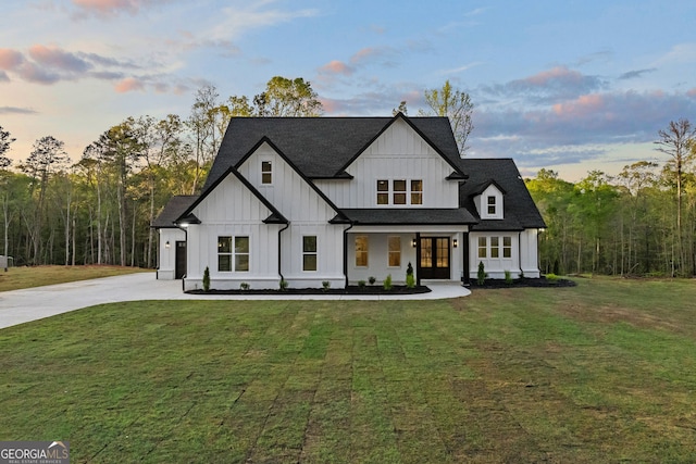 modern farmhouse featuring board and batten siding, a yard, roof with shingles, french doors, and concrete driveway