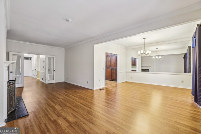 45 Willow Gln NE, Atlanta, GA 30342 - unfurnished living room featuring a notable chandelier, baseboards, ornamental molding, visible vents, and wood finished floors