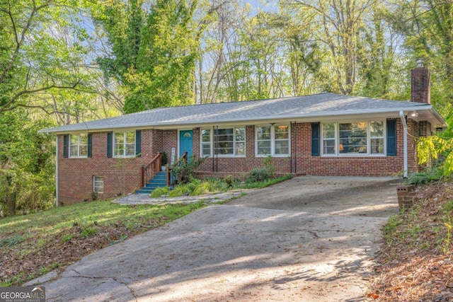 ranch-style house with concrete driveway, brick siding, and a chimney