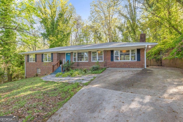 ranch-style house featuring concrete driveway, a chimney, a front yard, brick siding, and fence