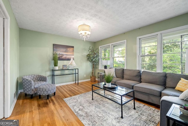 living room featuring baseboards, a notable chandelier, wood finished floors, and a textured ceiling