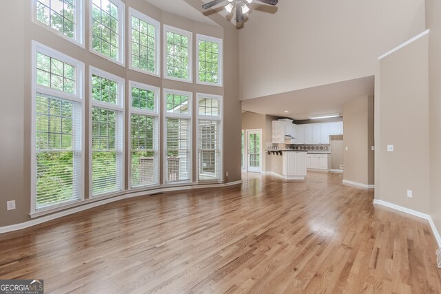 4106 Creekview Ridge Dr NE, Buford, GA 30518 - unfurnished living room featuring ceiling fan, a towering ceiling, light wood-style floors, and visible vents
