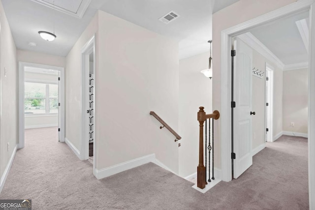 hall with visible vents, an upstairs landing, attic access, and carpet flooring
