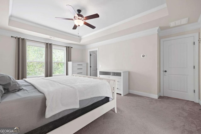 bedroom featuring a raised ceiling, light carpet, and baseboards