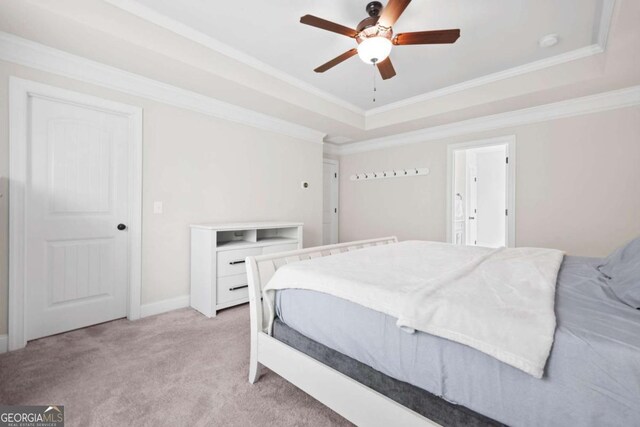 bedroom with baseboards, light colored carpet, crown molding, and a raised ceiling