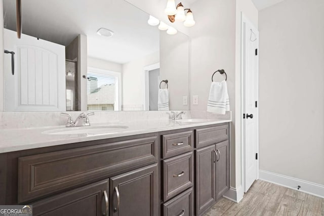 full bathroom featuring double vanity, baseboards, a sink, and wood finished floors