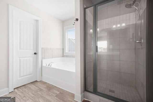 bathroom featuring a shower stall, a bath, and wood finished floors