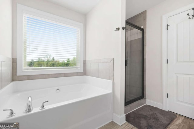full bathroom featuring a stall shower, a garden tub, wood finished floors, and baseboards