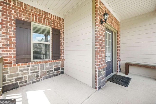 doorway to property with brick siding and a porch