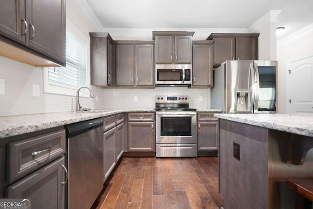 kitchen featuring a sink, ornamental molding, light stone countertops, and stainless steel appliances