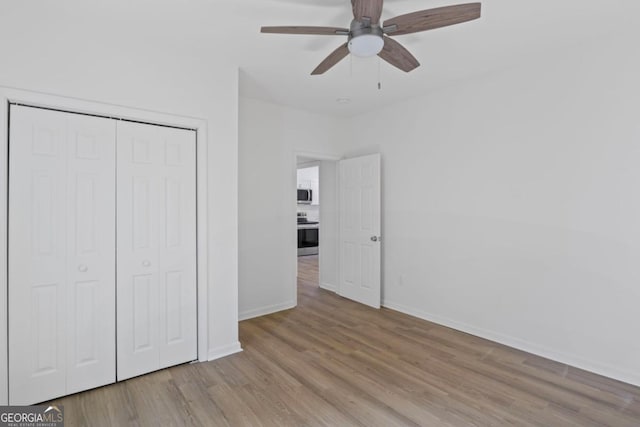 unfurnished bedroom with a closet, baseboards, a ceiling fan, and wood finished floors