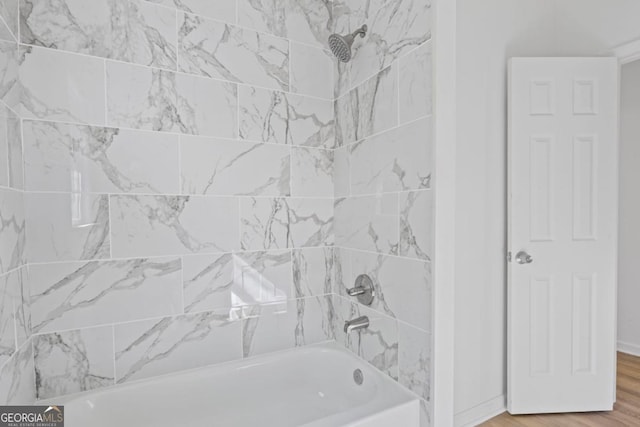 bathroom with wood finished floors, baseboards, and washtub / shower combination