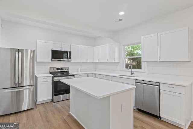 kitchen featuring light wood finished floors, white cabinetry, a sink, and appliances with stainless steel finishes