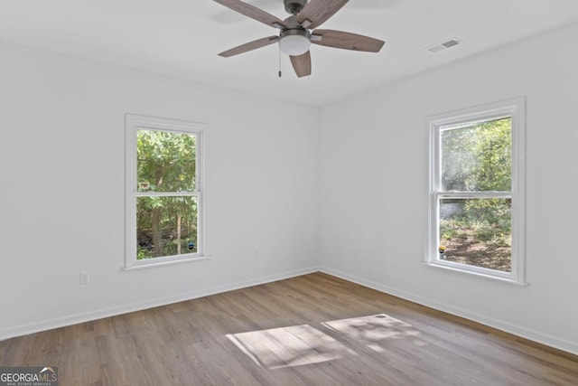 spare room with plenty of natural light, visible vents, and wood finished floors