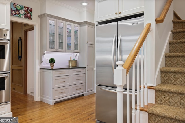 2000 Old Dominion Rd, Atlanta, GA 30350 - kitchen featuring glass insert cabinets, ornamental molding, dark countertops, appliances with stainless steel finishes, and light wood-style flooring